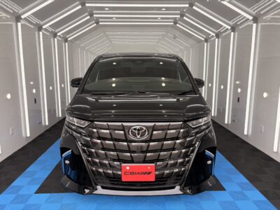 Front view of a black Toyota SUV in a bright white photo studio with vertical LED lights and a blue checkered floor.