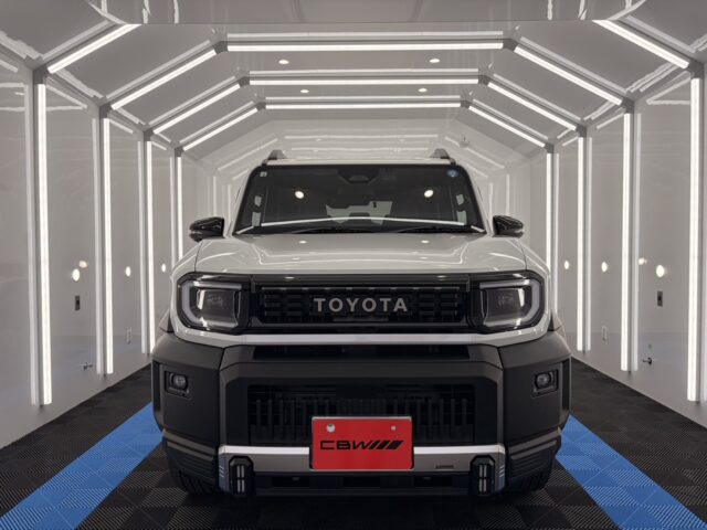 Front view of a white Toyota pickup in a bright white photography studio with vertical LED accent lighting on the walls and ceiling.