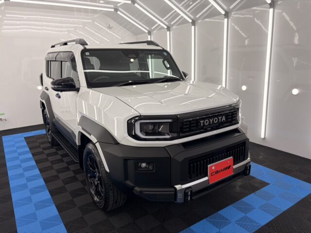 White Toyota pickup truck in a bright showroom, three-quarter front view with black grille and rugged bumper.
