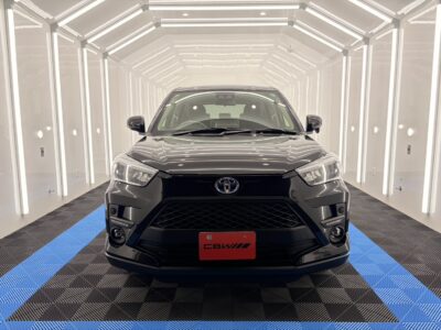 Front view of a black Toyota SUV in a bright, white tunnel with vertical LED strips and a blue-and-black checkered floor.